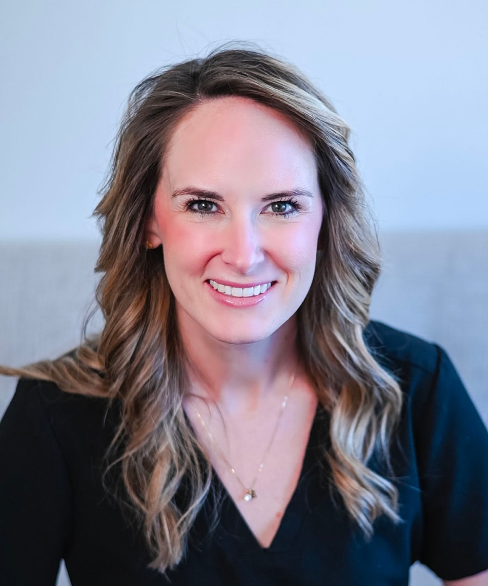 Smiling woman with wavy hair and black shirt.