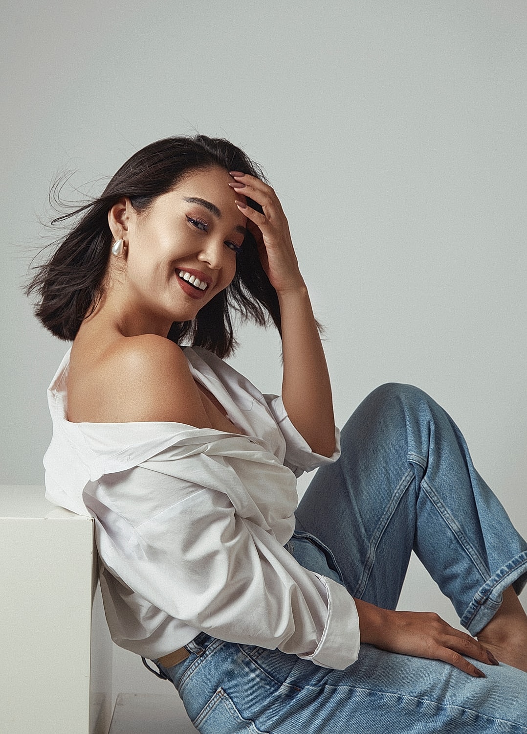 Smiling woman in casual outfit, playing with hair.