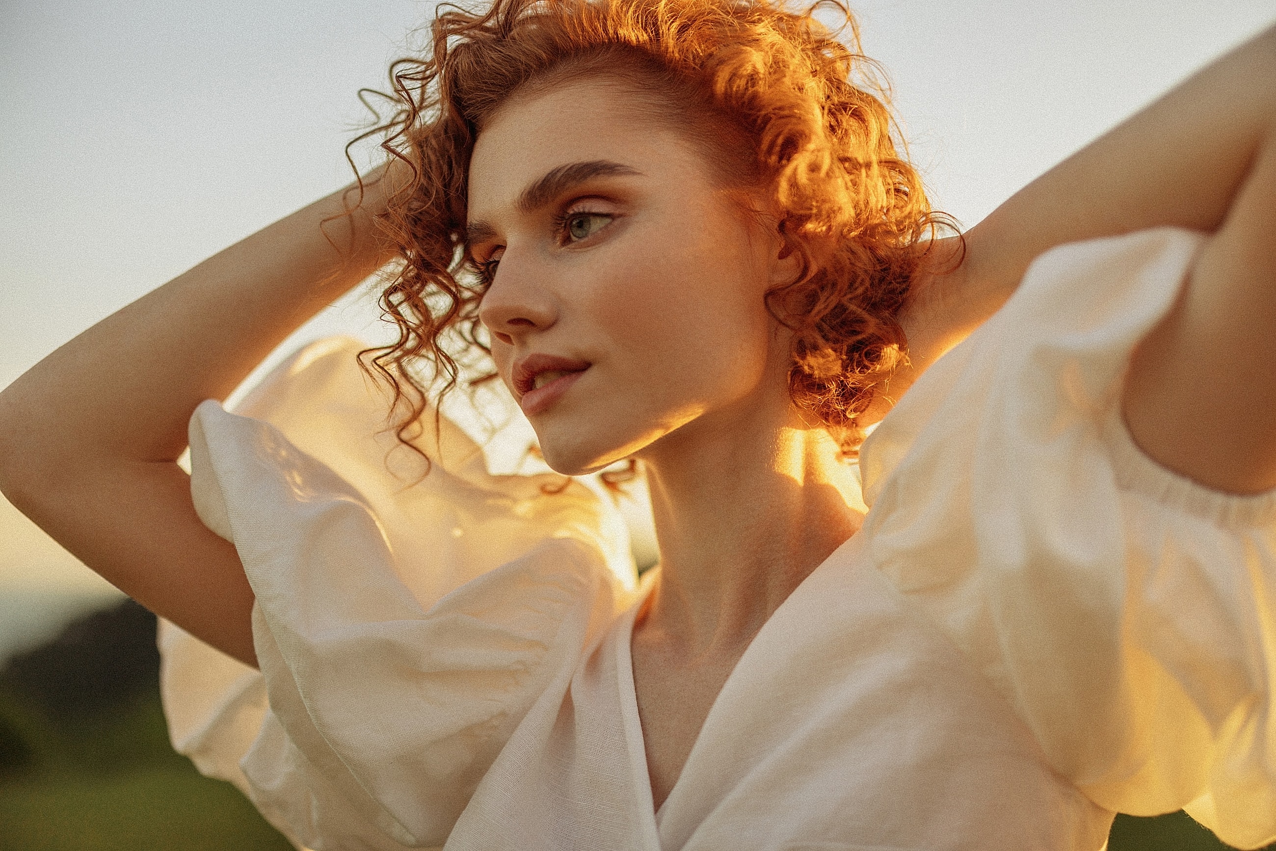 Woman with curly hair in golden sunlight.